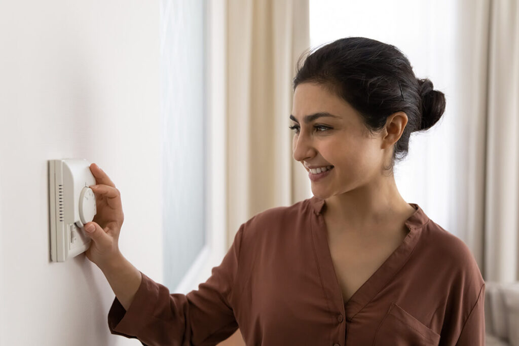 Happy woman adjusting thermostat