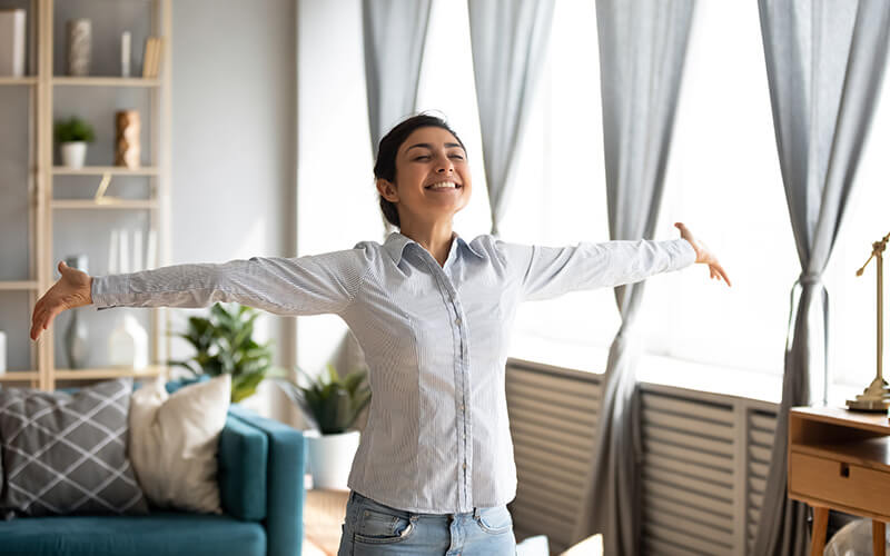 Woman with her arms out smiling in her home