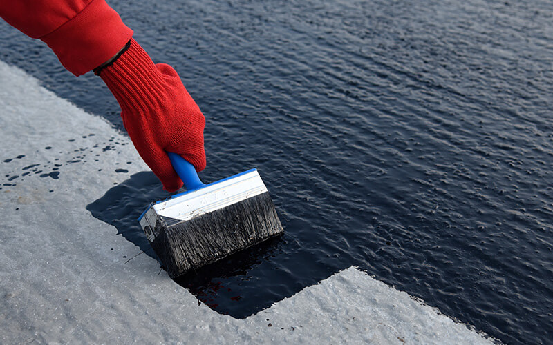 Worker applies bitumen mastic on the foundation
