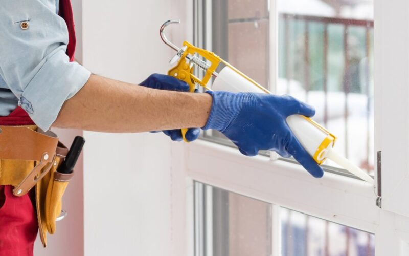 man caulking window to provide better air sealing