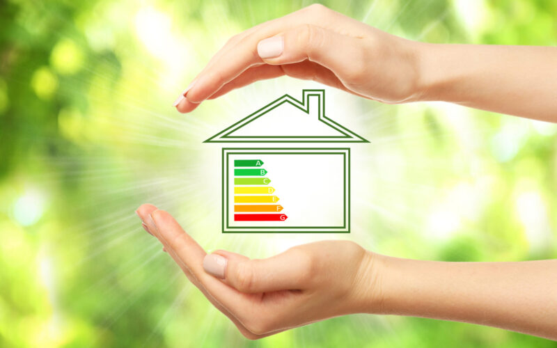 hands cupping a digital image of a home with yellow, green, and red lines showing energy efficiency levels