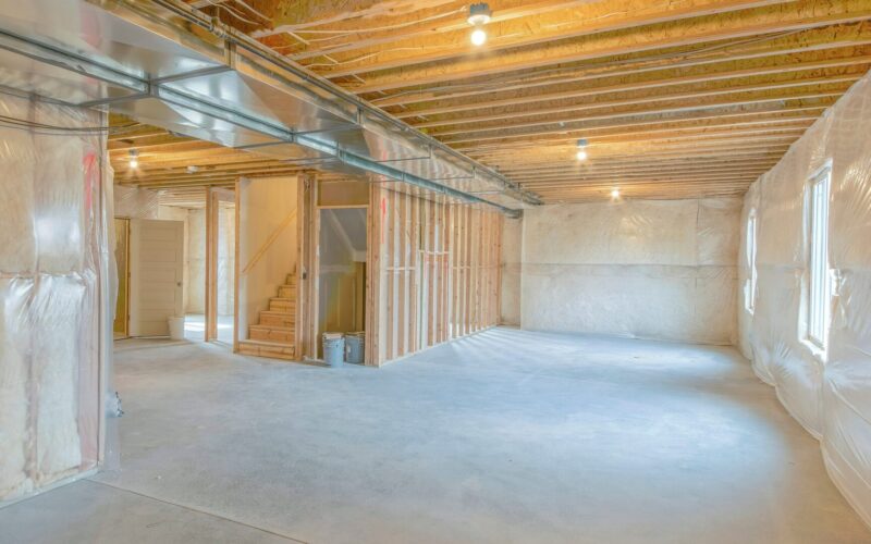 A new unfinished basement with plastic sheeting over insulated basement walls.