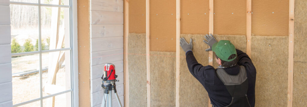 A worker installs installation batts on an exterior wall  