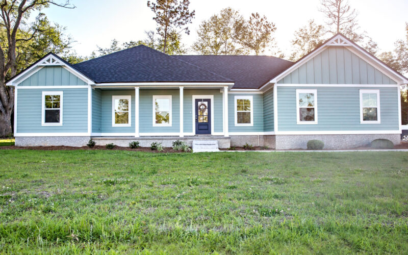 Front view of a blue, ranch-style home with a front yard 