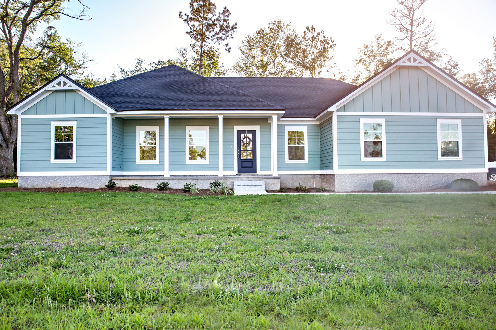 Front view of a blue, ranch-style home with a front yard 