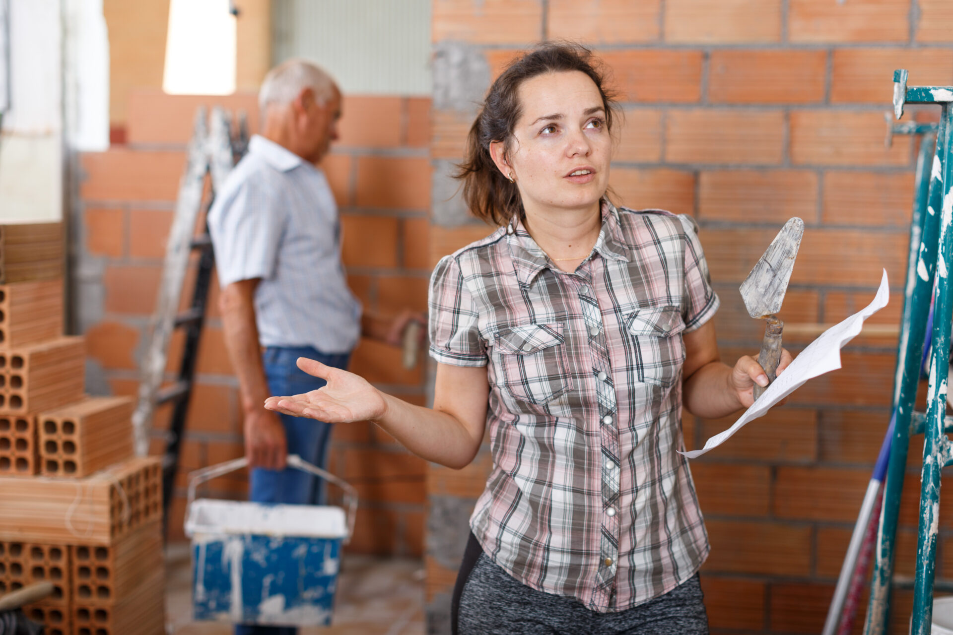 A confused homeowner stands in an uncompleted brick-walled room