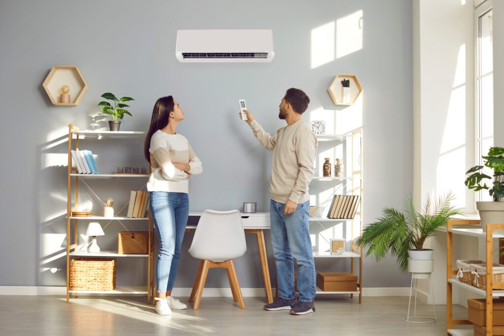 A man and woman trying to turn on their air conditioning unit with a remote