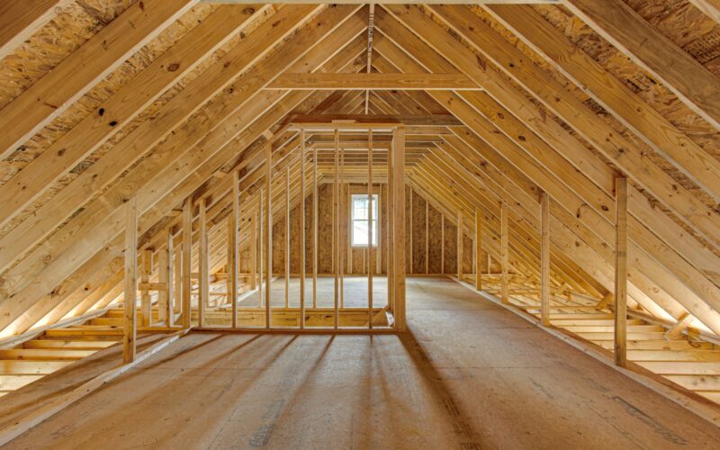 An unfinished attic space with bare rafters 